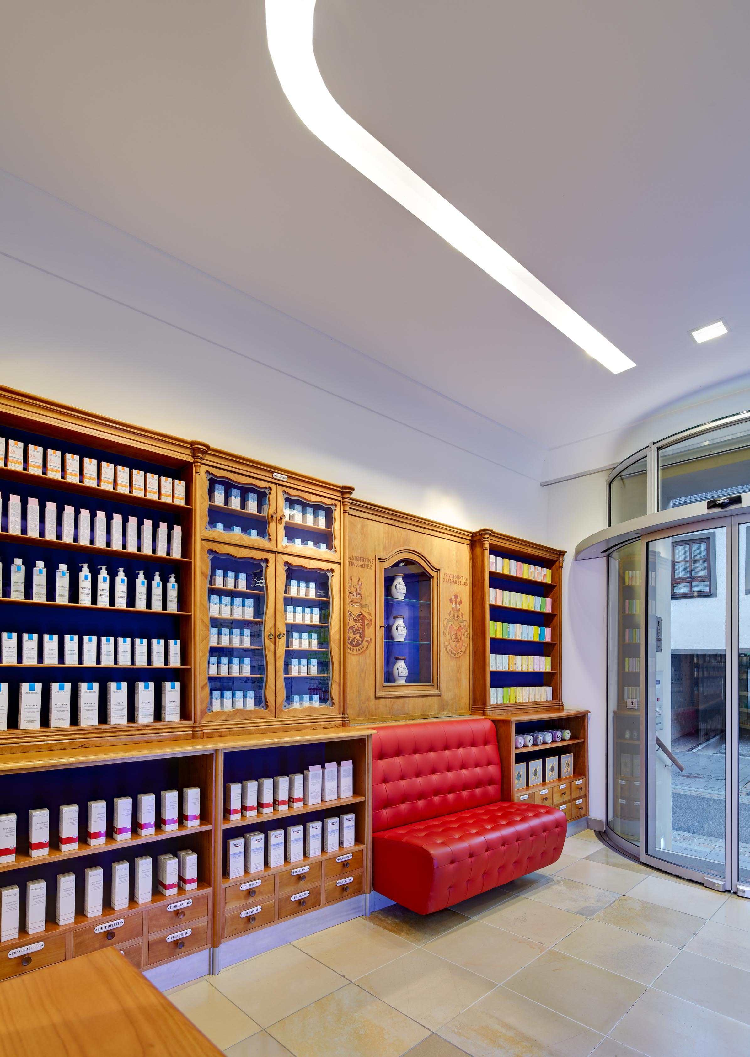 Blick vom Eingang in die historische Offizin mit Wartebank und restaurierter Apothekeneinrichtung
