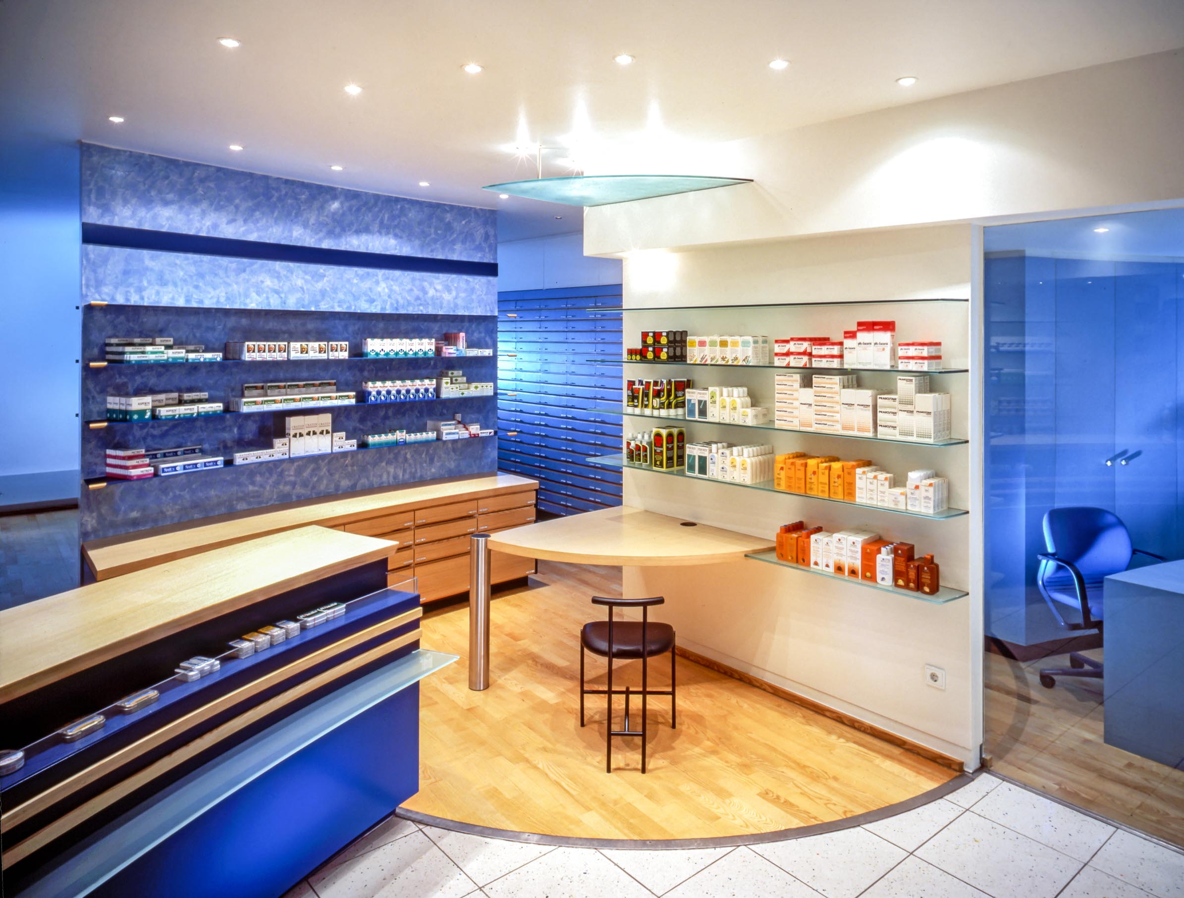 Zentraler Verkaufsraum der Apotheke mit ultramarinblauen Sichtwahlregalen und Handverkaufstresen