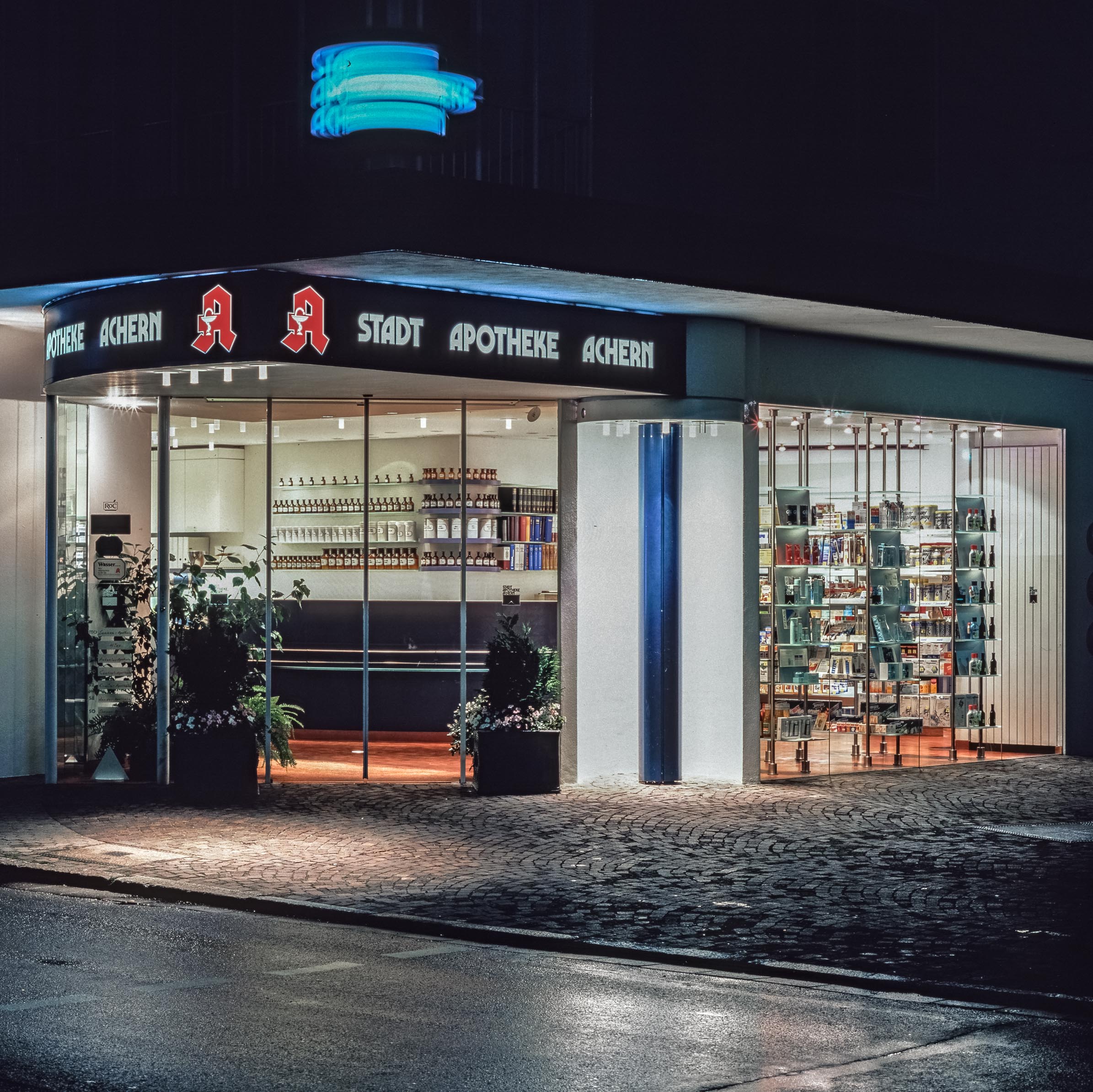 Stadt-Apotheke Achern, Eingang, Leuchtreklame, beleuchtete Schaufenster